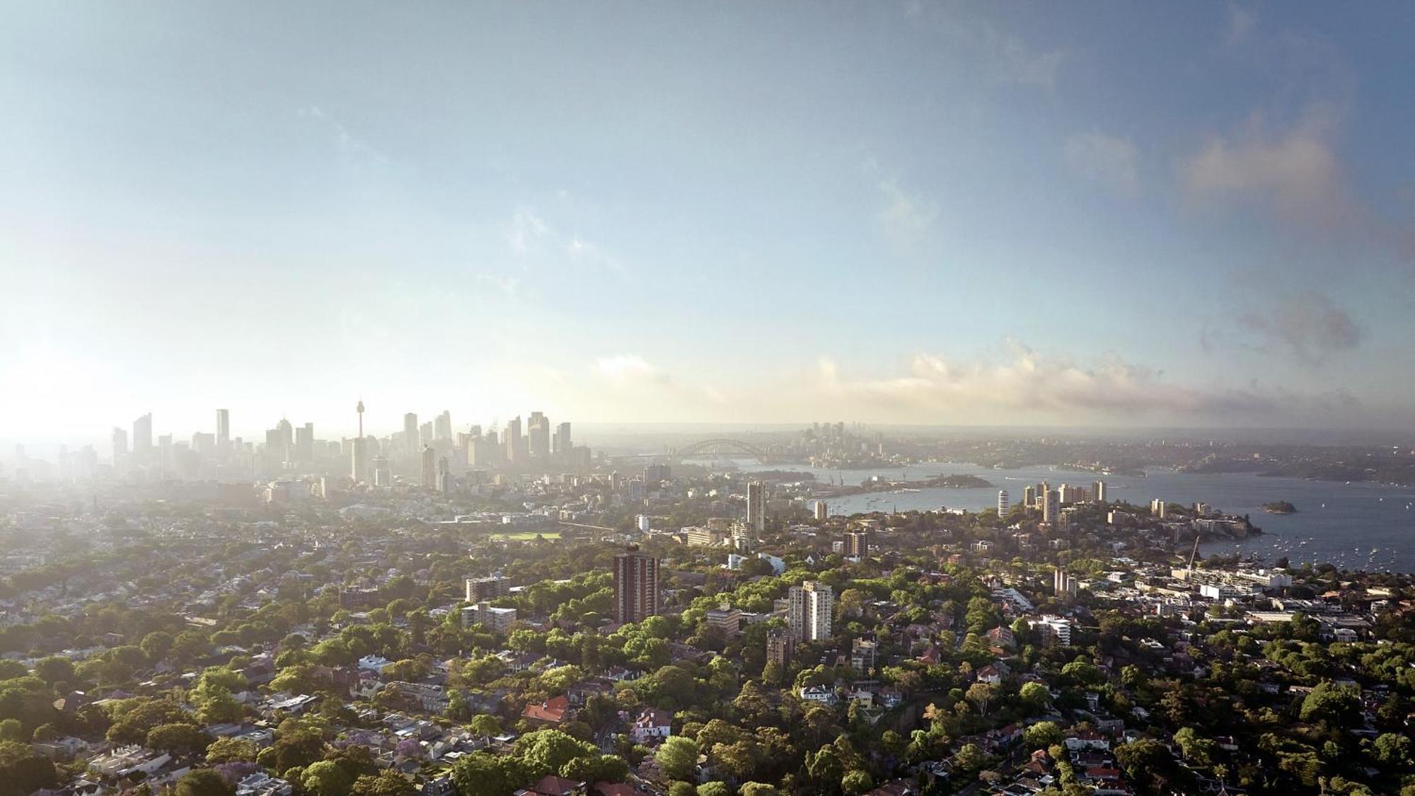 Meriton Suites Bondi Junction Сідней Екстер'єр фото The photo shows a panoramic view of a city skyline, likely taken from a high vantage point. In the foreground, there are lush green trees and buildings, suggesting a suburban area. As the view extends towards the background, tall skyscrapers dominate